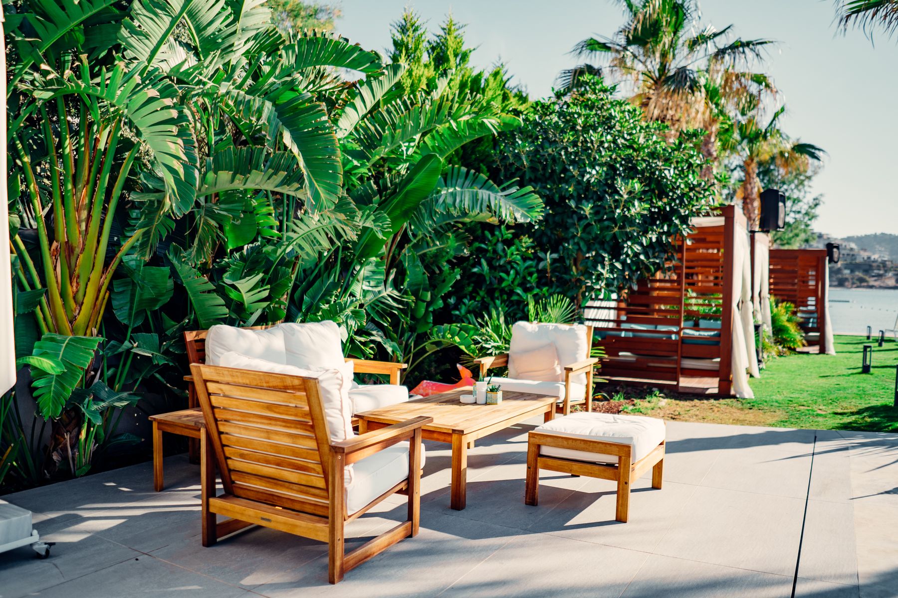 Wooden patio furniture on a stone patio surrounded by plants